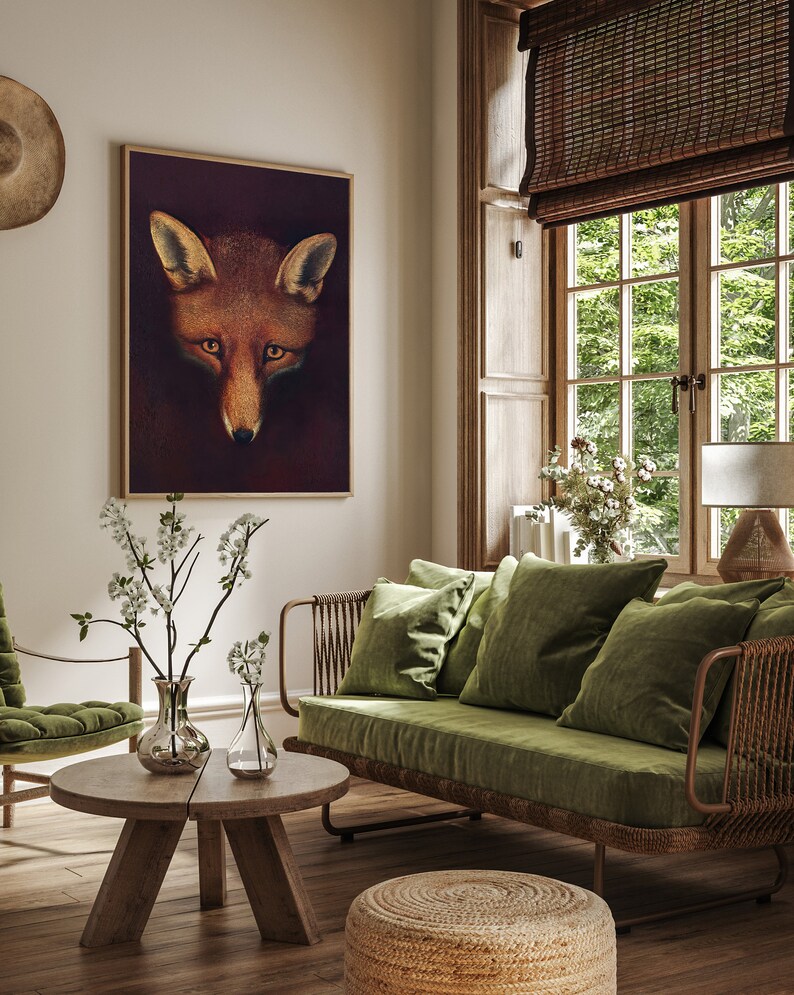 May include: A living room interior with a green velvet sofa, a wooden coffee table, and a framed print of a fox's face. The room has a rustic feel with wooden floors and a window with a bamboo blind.