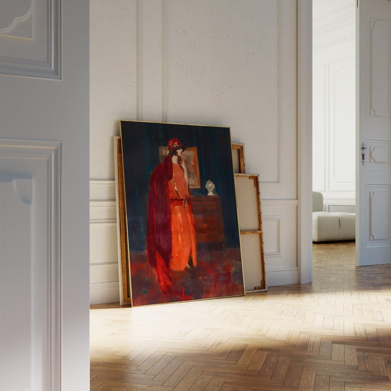 May include: A framed painting of a woman in a red dress and hat standing in front of a dark blue background. The painting is leaning against a white wall.