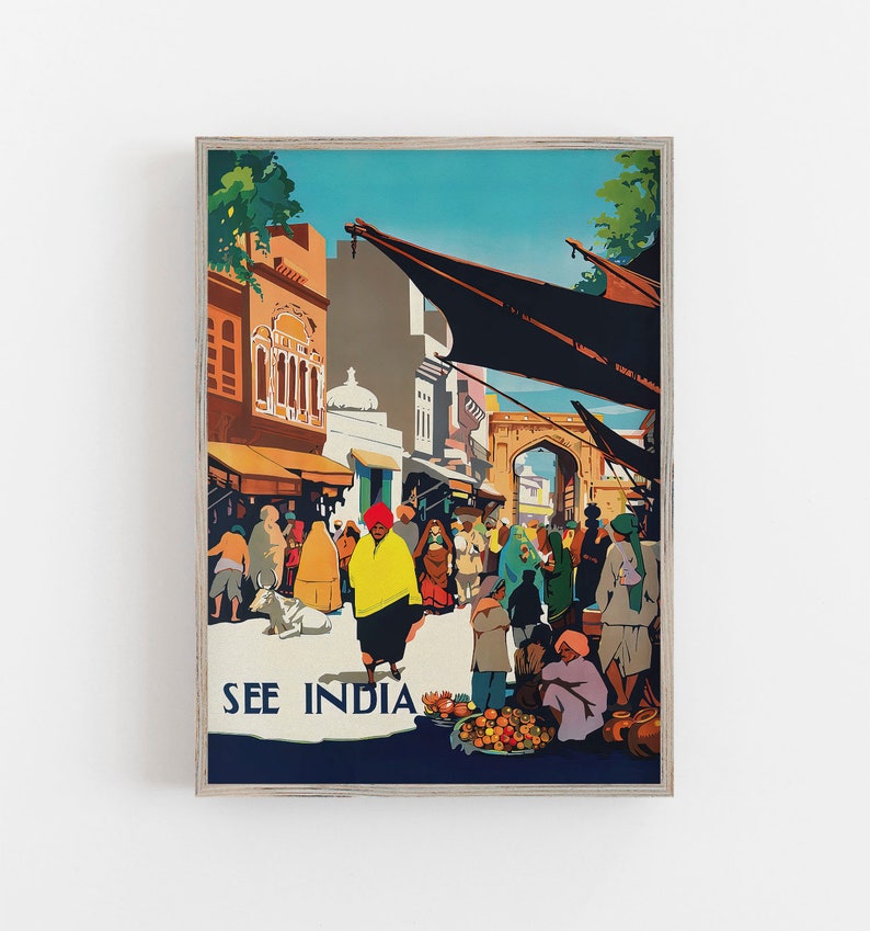 May include: A framed vintage travel poster with the text "SEE INDIA." The artwork depicts a bustling street scene with people in traditional clothing, buildings, and a cow. The color palette includes shades of orange, yellow, blue, and green.