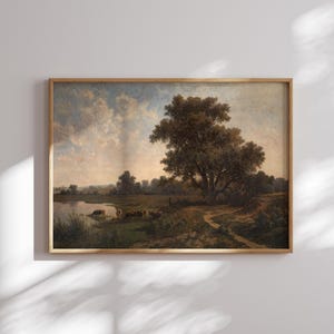 K&ouml;nnte beinhalten: Ein gerahmtes Landschaftsgem&auml;lde, das eine l&auml;ndliche Szene mit einem gro&szlig;en Baum im Vordergrund, einem Fluss und einer Gruppe von Rindern in der Ferne zeigt. Der Himmel ist hellblau mit flauschigen wei&szlig;en Wolken.