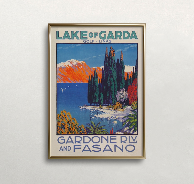 May include: A framed vintage travel poster for Lake Garda, Italy, featuring a scenic view of the lake and mountains. The poster has text that reads "Lake of Garda Golf Links" and "Gardone Riv. and Fasano". The artwork uses a vibrant color palette of blues, oranges, and greens.