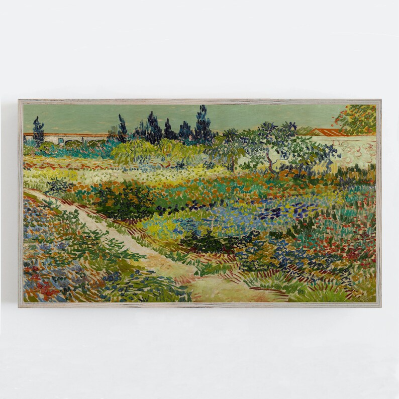 May include: A framed print depicting a garden scene with a path winding through colourful flowers and plants. The artwork uses greens, blues, yellows, and reds, with a light blue sky and a white wall. The frame is a light wood colour.