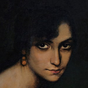 Pode incluir: Um retrato de perto de uma mulher com cabelo escuro e olhos castanhos. Ela est&aacute; usando um par de pequenos brincos redondos laranja. O fundo &eacute; escuro.