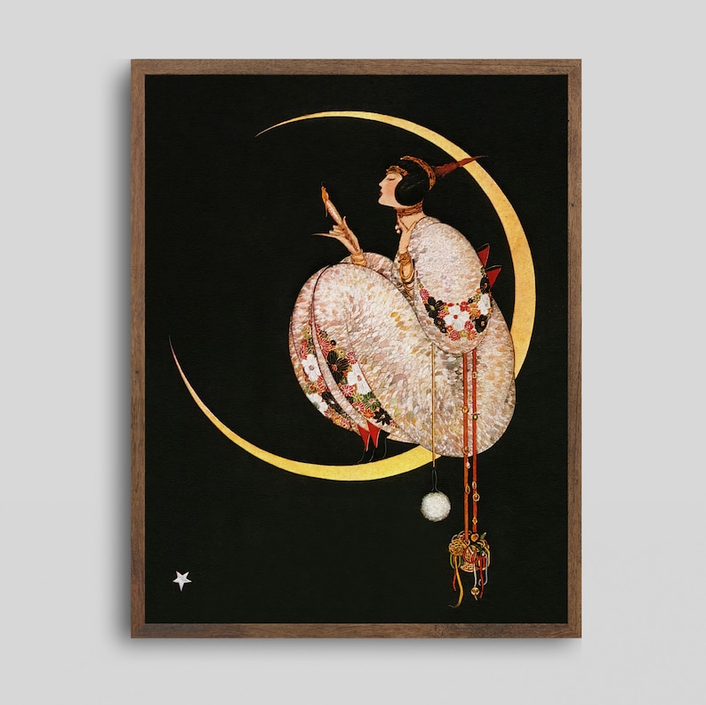 Op de afbeelding: Een ingelijste kunstdruk met een figuur in een wit gewaad met patronen, zittend op een grote gouden maansikkel tegen een zwarte achtergrond. De figuur houdt een klein voorwerp vast, met een witte pompon en decoratieve kwastjes onder de maan.