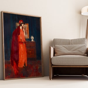 May include: A framed painting of a woman in a red dress and a red hat standing in a room with a dark blue wall. The woman is looking to the side and holding a small object in her hand. There is a dresser with a lamp on it in the background.