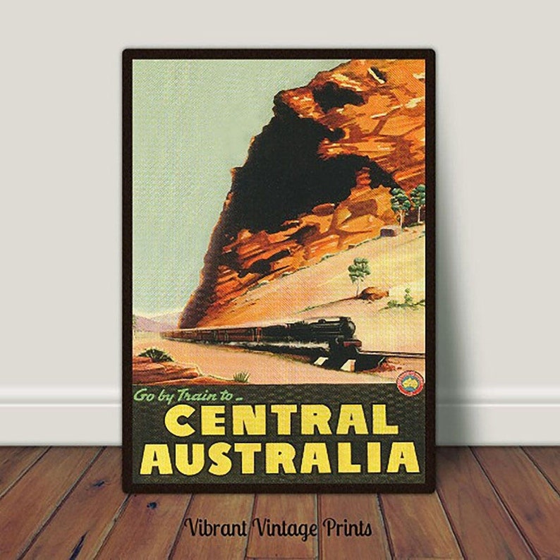 Pu&ograve; includere: Poster di viaggio vintage per l'Australia centrale, raffigurante un treno che viaggia attraverso un paesaggio desertico con una grande formazione rocciosa. Il poster ha una cornice marrone e il testo "Go by Train to - CENTRAL AUSTRALIA."