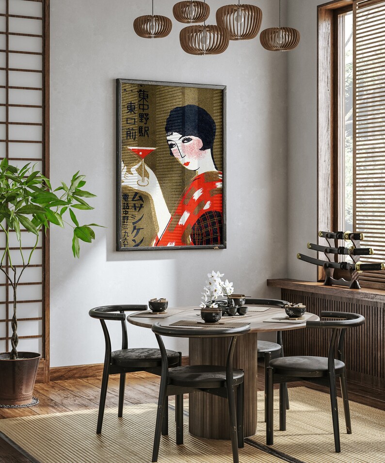 K&ouml;nnte beinhalten: Ein gerahmtes japanisches Vintage-Poster mit einer Frau in einem roten Kimono, die einen Cocktail h&auml;lt. Das Kunstwerk wird in einem Esszimmer mit einem runden Tisch, schwarzen St&uuml;hlen und Holzakzenten ausgestellt. Dekorative H&auml;ngelampen befinden sich &uuml;ber dem Tisch.