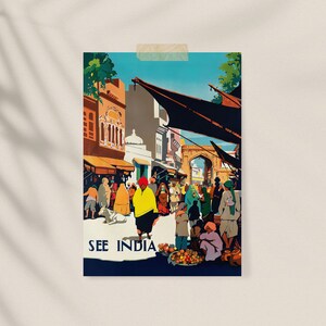 May include: A vintage travel poster with the text "SEE INDIA" depicts a bustling street scene. People in colorful clothing and turbans are gathered near buildings and a large archway. The poster has a retro travel aesthetic.