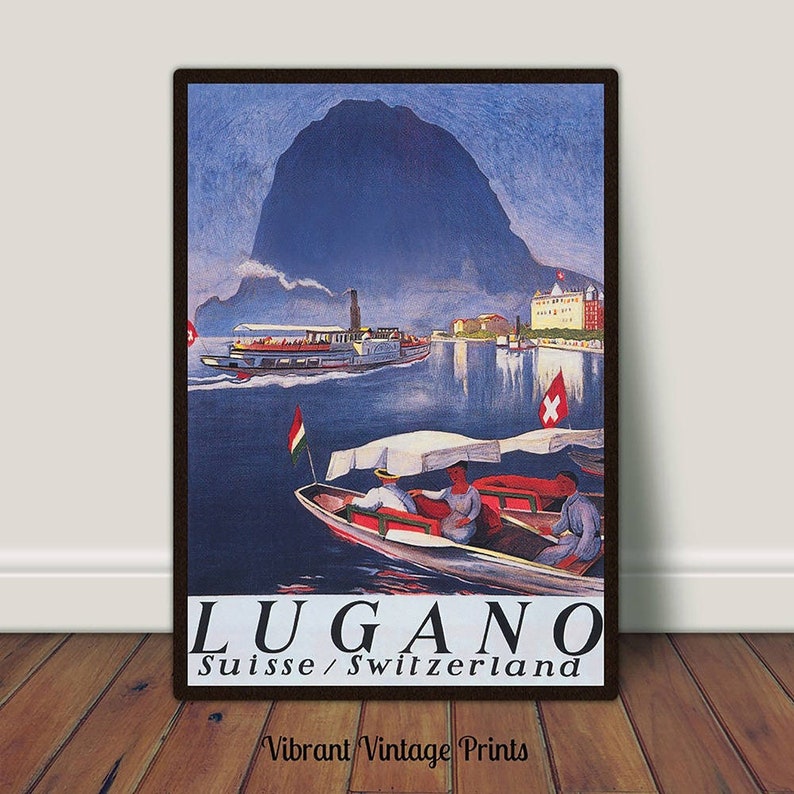 May include: A framed vintage travel poster for Lugano, Switzerland. The image shows a lake scene with boats and a mountain. The poster has a dark brown frame and the text "LUGANO Suisse / Switzerland". The words "Vibrant Vintage Prints" are at the bottom.