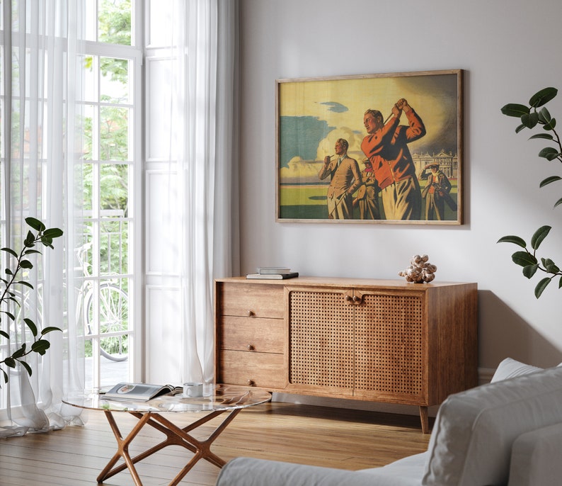 Pu&ograve; includere: Un soggiorno in stile moderno di met&agrave; secolo con un mobile in legno con una porta in rattan intrecciato. Il mobile &egrave; decorato con una stampa vintage incorniciata di tre uomini che giocano a golf. La stanza presenta anche un tavolino da caff&egrave; in vetro e un divano bianco.