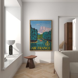 May include: Vintage travel poster featuring a scenic landscape with mountains, trees, and a river. The poster is in a wooden frame and has the text "CANADA AIR FRANCE" at the bottom.