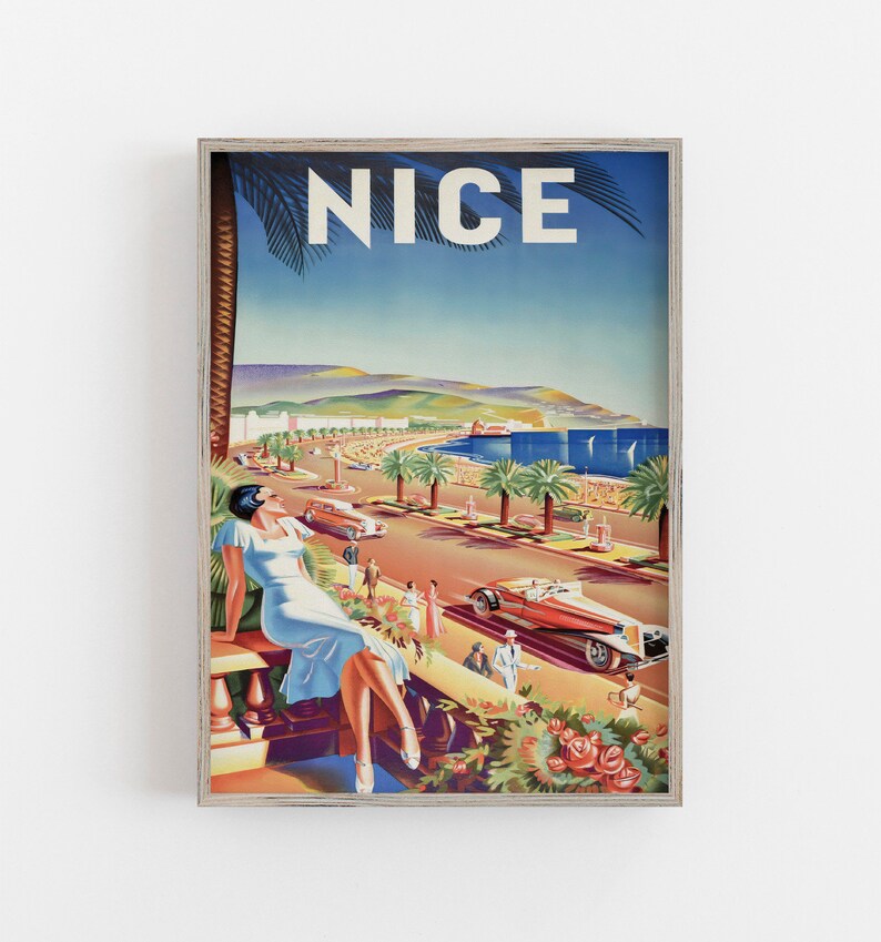 Puede incluir: P&oacute;ster de viaje vintage enmarcado de Niza, Francia. La obra de arte representa a una mujer con un vestido azul claro, palmeras, coches cl&aacute;sicos y la palabra "NICE" en blanco sobre un cielo azul. El p&oacute;ster est&aacute; enmarcado en un marco de madera clara.