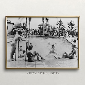 May include: A black and white vintage photograph of people swimming and relaxing around a pool. The pool is surrounded by trees and a building in the background.
