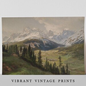 Op de afbeelding: Een landschapsschilderij met een vallei en een klein dorpje tussen groene hellingen en hoge dennenbomen, leidend naar grillige, besneeuwde bergtoppen onder een bewolkte lucht. De tekst VIBRANT VINTAGE PRINTS staat onderaan de afbeelding.