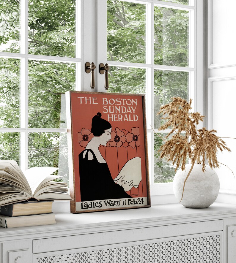 May include: A framed vintage poster for The Boston Sunday Herald, showing a woman in black reading a paper, set against a red background with floral accents. The text "Ladies Want it Feb 24" is visible.