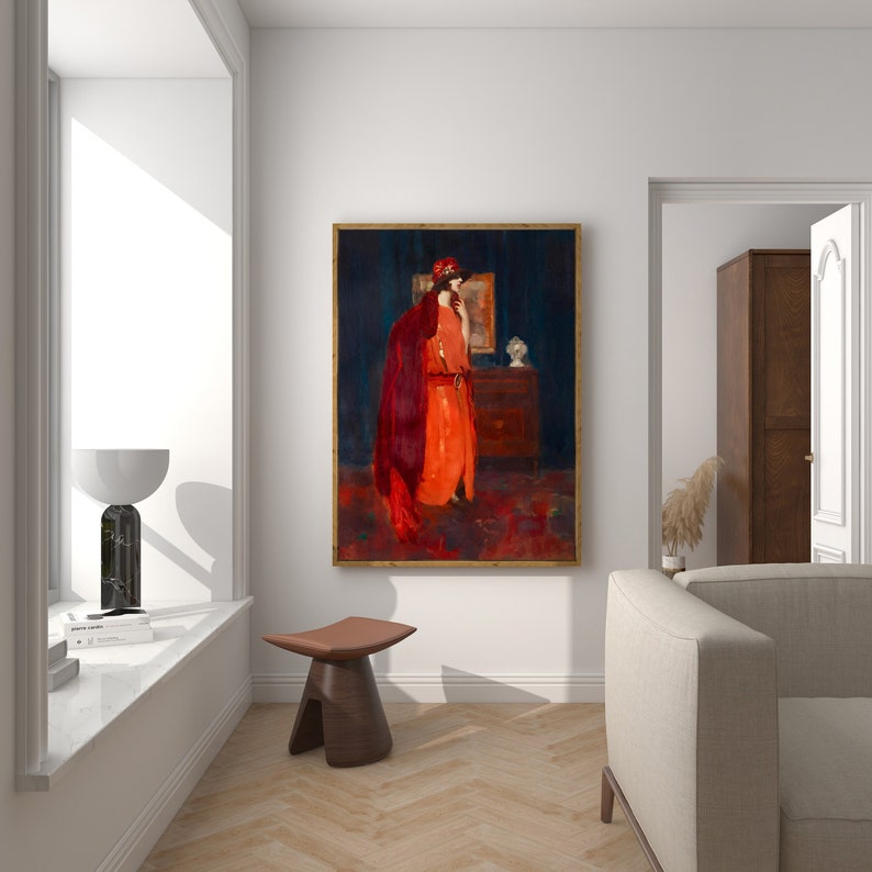 May include: A painting of a woman in a red dress and cloak standing in front of a dresser. The painting is framed in gold and hangs on a white wall.