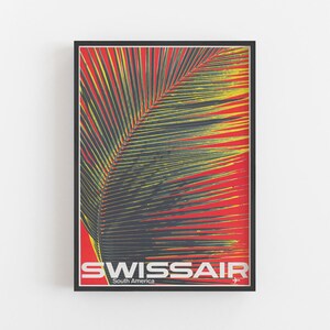 May include: A framed vintage travel poster for Swissair, featuring a palm leaf against a red background. The poster has the text "SWISSAIR South America" in white and silver, with a small airplane graphic.