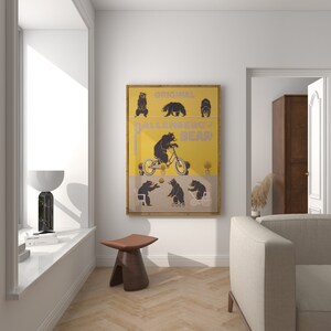 Op de afbeelding: Een ingelijste print met een gele en beige achtergrond, met illustraties van beren. De print bevat de tekst "ORIGINAL BALLENBERG BEAR" en toont beren in verschillende poses, waaronder fietsen en op een stoel zitten.