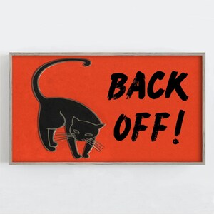 May include: A framed print featuring a black cat silhouette on a vibrant orange background. Bold black text reads "BACK OFF!" The artwork has a minimalist design, perfect for Halloween or cat lovers.