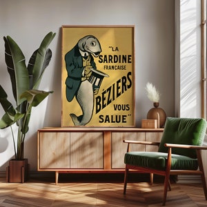 K&ouml;nnte beinhalten: Ein rechteckiges gerahmtes Poster mit gelbem Hintergrund und einer schwarz-wei&szlig;en Illustration eines Fisches in Anzug und Zylinder. Der Text LA SARDINE FRAN&Ccedil;AISE B&Eacute;ZIERS VOUS SALUE ist in fetten schwarzen Buchstaben auf der rechten Seite zu sehen.