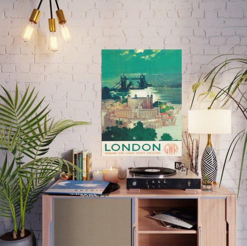 May include: Vintage travel poster advertising a trip to London, England. The poster features a colorful illustration of Tower Bridge and the Tower of London. The text on the poster reads "London GWR Enquire for Cheap Ticket Facilities".