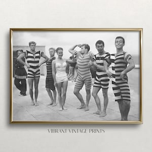 Puede incluir: Fotografía en blanco y negro de siete personas con trajes de baño a rayas. Las personas están de pie sobre una superficie de azulejos y parecen estar posando para una foto. La foto está enmarcada en un marco dorado.