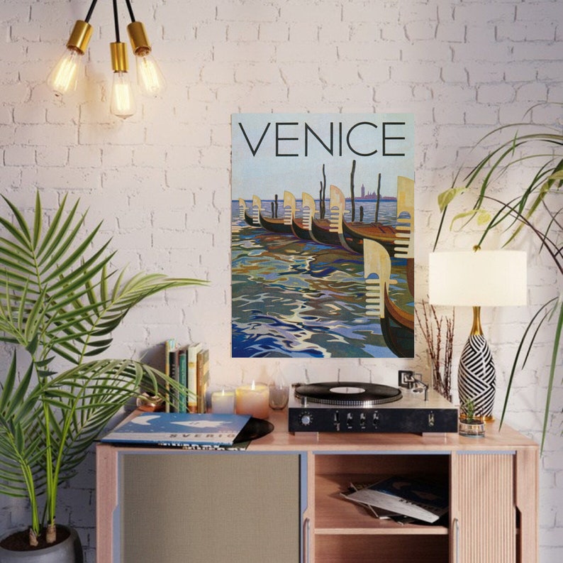 May include: A poster titled "Venice" depicts a row of gondolas on the water. The artwork features a blue and brown color palette, with the word "Venice" in large, bold letters at the top. The gondolas are lined up along the water's edge.