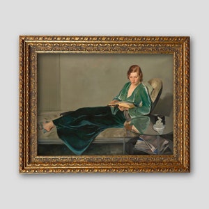 May include: A painting of a woman in a green velvet robe sitting on a couch and reading a book. The woman is wearing a green velvet robe and has her hair pulled back. She is sitting on a couch with a white cushion and a glass table in front of her. The painting is framed in a gold frame.