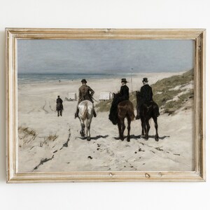 May include: An antique framed print depicts a beach scene with three people riding horses along the sandy shore. The artwork features a muted color palette with a cloudy sky and distant figures, evoking a sense of nostalgia.