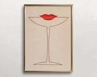 May include: A framed wall art print featuring a minimalist line drawing of a martini glass in dark red ink on a light beige background. A pair of solid red lips is positioned directly above the rim of the glass, creating a stylized graphic.