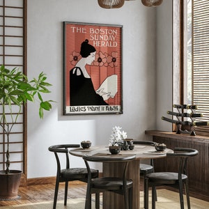 May include: A framed vintage poster for The Boston Sunday Herald, featuring a woman reading, with text "Ladies Want it Feb 24". The poster hangs above a round wooden dining table with four black chairs. The room has a Japanese-inspired design.