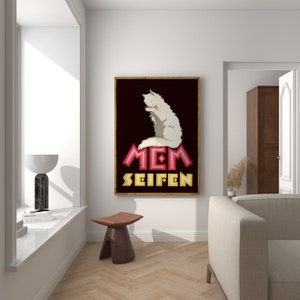May include: A framed art print featuring a white cat grooming itself, set against a dark background. The artwork includes the text "MEM SEIFEN" in pink and yellow. The print is displayed in a well-lit room with a modern aesthetic.