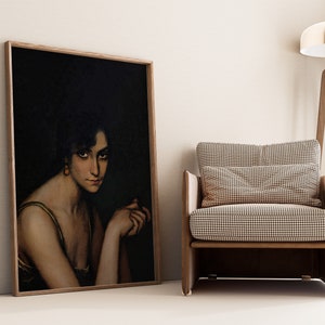 Pode incluir: Um retrato emoldurado de uma mulher com cabelo escuro e um vestido verde claro. O retrato est&aacute; sobre um fundo escuro e &eacute; emoldurado em uma moldura de madeira clara.