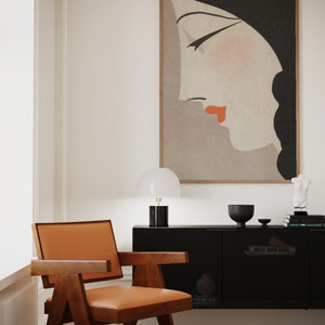 May include: A mid-century modern interior featuring a wooden chair with an orange leather seat, a black cabinet, and a framed artwork of a woman's profile. A white lamp and decorative items sit atop the cabinet.