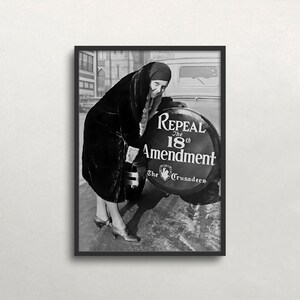 May include: Black and white framed print of a woman leaning against a car, with a sign that reads "Repeal the 18th Amendment" and "The Crusaders". The woman is wearing a long coat and hat.