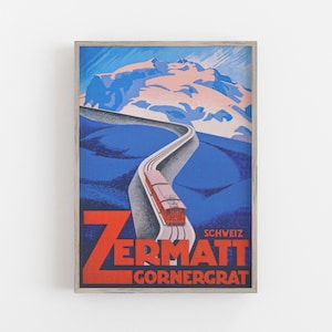 May include: Framed vintage travel poster for Zermatt, Switzerland, featuring a red train ascending a winding track towards a snow-capped mountain. The poster has a blue and red color scheme with the text "Zermatt Gornergrat".