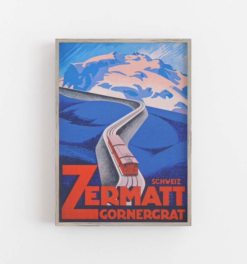 May include: Framed vintage travel poster for Zermatt, Switzerland, featuring a red train ascending a winding track towards a snow-capped mountain. The poster has a blue and red color scheme with the text "Zermatt Gornergrat".