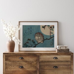 May include: A framed print of a Japanese woodblock print depicting an owl perched on a branch with a full moon in the background. The print is in shades of blue, white, and brown. The Japanese text in the print reads "Fukuro no zu".