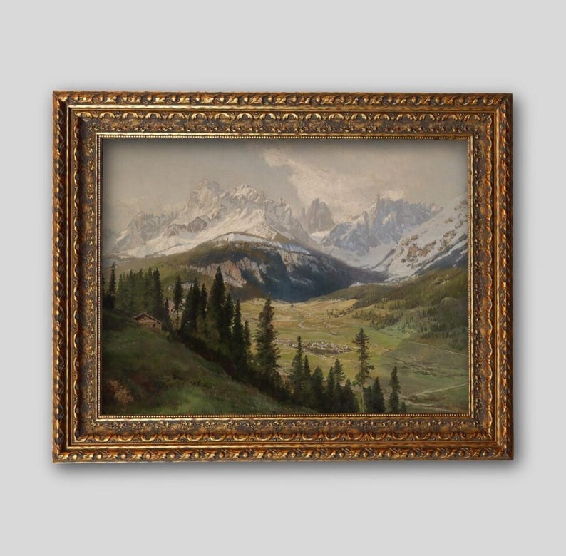Op de afbeelding: Een landschapsschilderij in een decoratieve gouden lijst met een bergketen met besneeuwde toppen, een groene vallei en een groep bomen op de voorgrond. De sc&egrave;ne toont een kleine hut verscholen tussen de donkergroene dennenbomen.