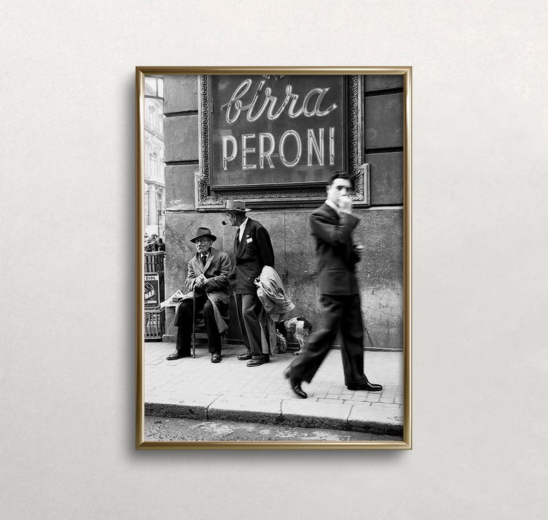 Pu&ograve; includere: Fotografia in bianco e nero incorniciata con una scena di strada con tre uomini in abiti e cappelli. Un'insegna sopra recita "Birra Peroni". Un uomo fuma, un altro &egrave; seduto su una panchina e un terzo cammina sul marciapiede.