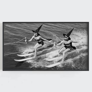 Peut inclure: Deux personnes portant des chapeaux de sorcière et des maillots de bain noirs font du ski nautique sur un lac. La photo est en noir et blanc.