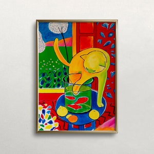 May include: A framed art print featuring a yellow cat reaching into a fishbowl with red fish. The artwork has a vibrant color palette with a blue table, green grass, and a red patterned background. Oranges and lemons are on the table.