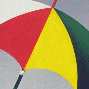 May include: A multi-coloured umbrella with a segmented design. The umbrella has panels of red, yellow, green, and white. The handle is black with a white ball at the top. The background is grey.