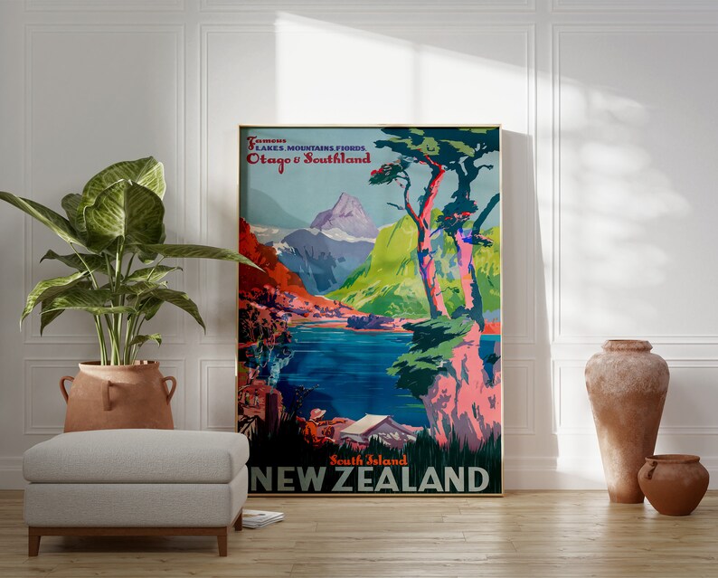 May include: A vintage travel poster advertising New Zealand's South Island. The poster features a colorful illustration of mountains, a lake, and a large tree with pink and green foliage. The text on the poster reads "South Island NEW ZEALAND" and "Fiords Lakes Mountains Fiords Otago & Southland".