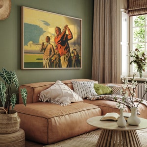 Pu&ograve; includere: Un poster vintage di tre uomini che giocano a golf su un campo verde. Il poster &egrave; incorniciato e appeso a una parete verde in un soggiorno con un divano in pelle marrone e un tavolino da caff&egrave;.