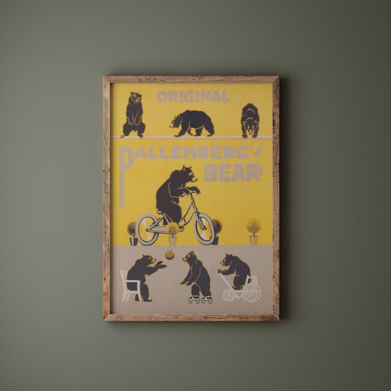 Op de afbeelding: Een ingelijste print met een gele achtergrond en zwarte berenillustraties. De print leest "ORIGINAL DALLENBERG'S BEAR" en toont beren op een koord, fietsend en spelend met een bal. Het frame is gemaakt van lichtbruin hout.
