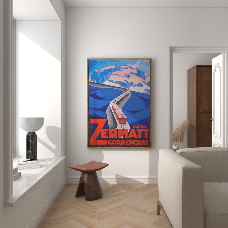 May include: A framed vintage travel poster for Zermatt, Switzerland, featuring a red train ascending a winding road towards snow-capped mountains. The poster has a blue and white color scheme with the text "Zermatt Gornergrat" in bold red letters.