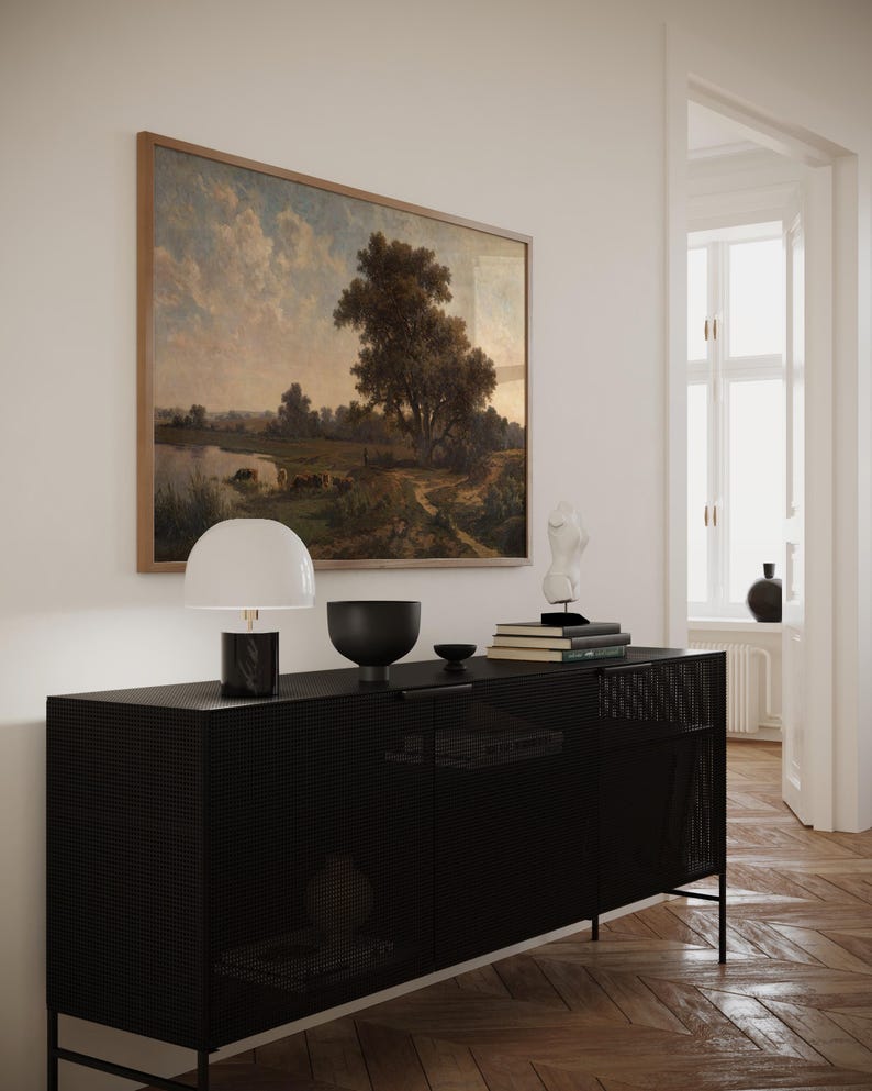 K&ouml;nnte beinhalten: Ein schwarzer Metallschrank mit einer Drahtgitterfront, eine wei&szlig;e Lampe mit einem wei&szlig;en Schirm, eine schwarze Schale und eine wei&szlig;e Skulptur darauf. Der Schrank steht vor einer wei&szlig;en Wand mit einem gerahmten Landschaftsbild.