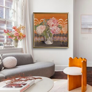 May include: A framed painting of pink peonies in a silver vase against a background of orange and black geometric patterns.