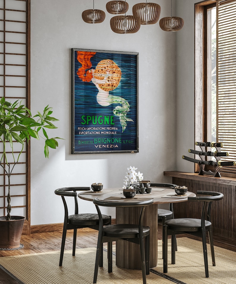 May include: A round wooden dining table with four black chairs. The table is set with a white vase with white flowers, a bowl of chopsticks, and a bowl of soy sauce. A vintage poster with a mermaid and the text "SPUGNE FELICA LAVORAZIONE PROPRIA ESPORTAZIONE MONDIALE BENEDETTO BRIGNONE & FIGLI VENEZIA" hangs on the wall behind the table.
